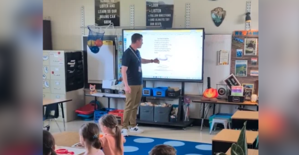 A teacher speaking in front of a classroom of students.