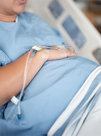 A pregnant patient resting in a hospital bed with an IV line.